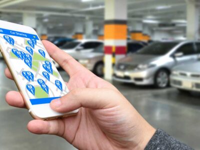 Bildelning - man söker efter ledig bilpoolsbil i en mobilapp