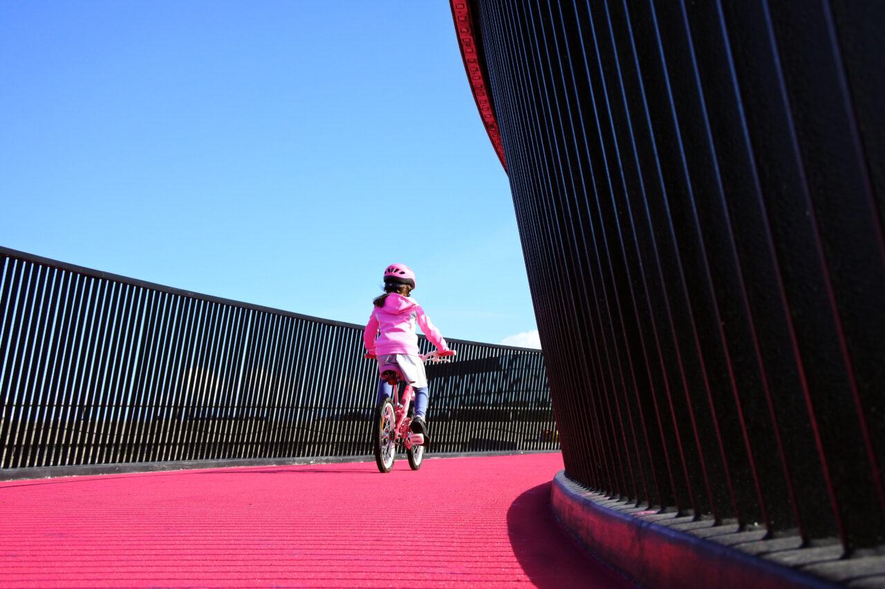 Flicka som cyklar på cykelväg i rosa