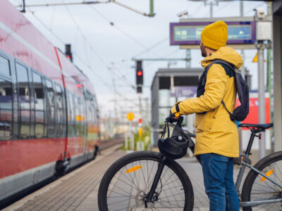 Man med cykel står på perrong och väntar på att tågens dörrar ska öppnas och han kan gå på.
