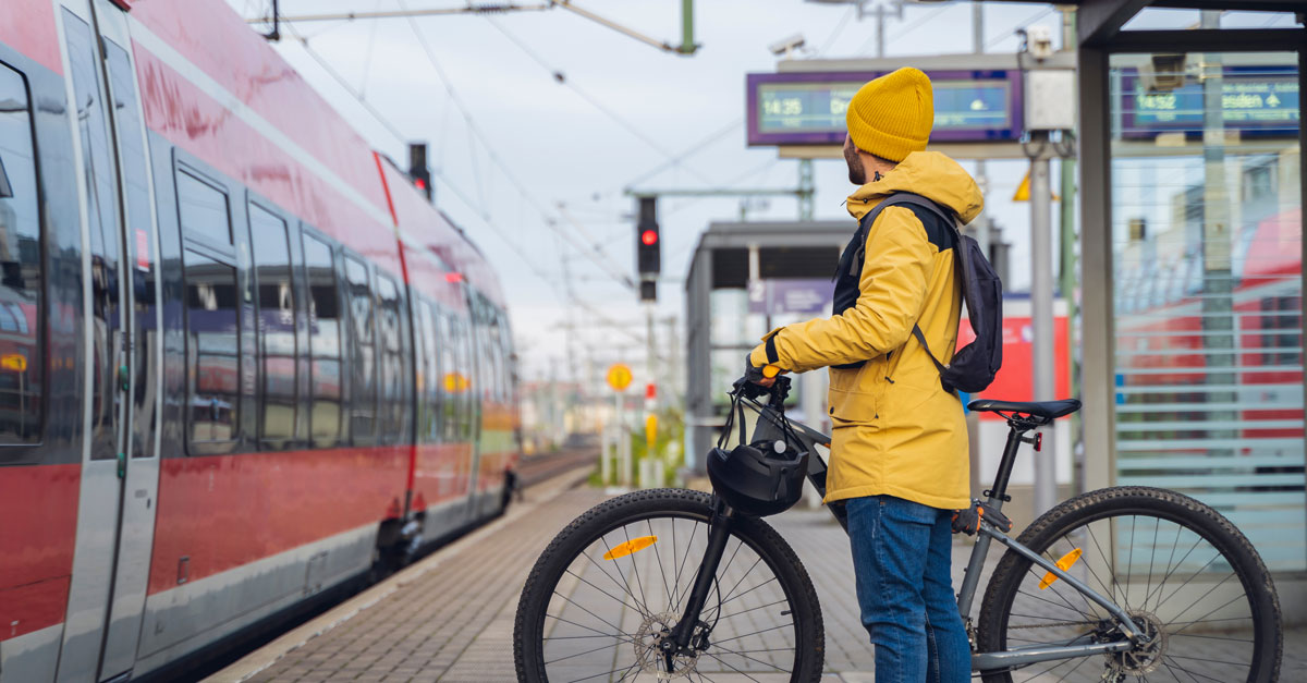 Man med cykel står på perrong och väntar på att tågens dörrar ska öppnas och han kan gå på - cykel i kollektivtrafik