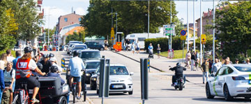 Järnvägskorsning i Varberg med många trafikanter, bilister, cyklister och fotgängare.