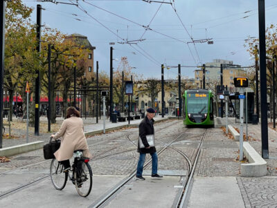En cyklist och en fotgängare passerar spåren för Lunds spårväg.