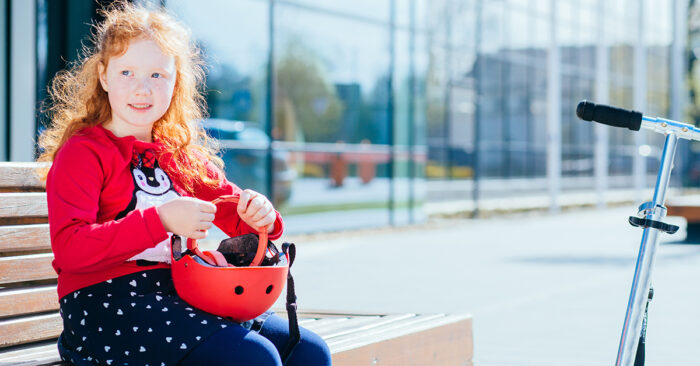 flicka som sitter på bänk med cykelhjälm i handen