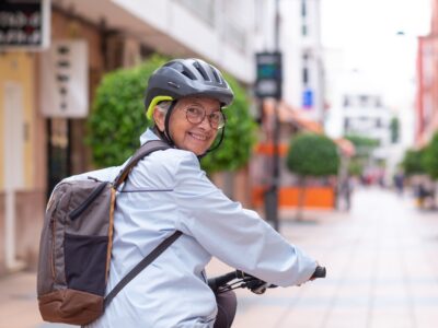 senior dam med ryggsäck cyklar i stan